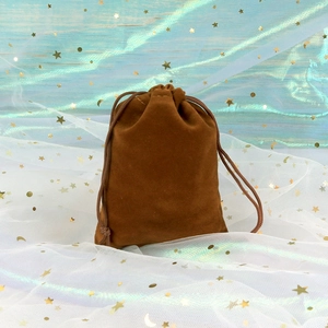 Detailed view of a brown velvet drawstring pouch for jewelry storage on decorative background
