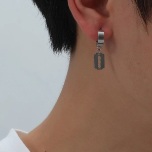 Detailed close-up of a stainless steel razor blade pendant hanging from a silver ear hoop
