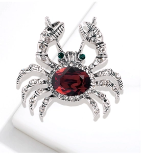 Macro shot of crab brooch featuring red oval gemstone and sparkling crystal inlay