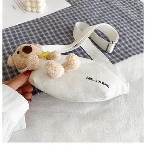 Detail of white canvas crossbody bag with a cute brown plush bear and adjustable strap