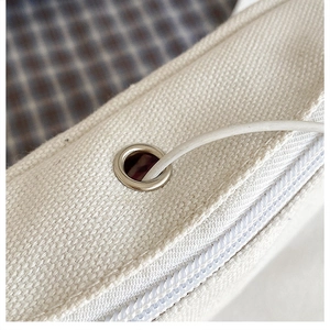 Detailed close-up of cream canvas fabric texture with metal grommet and white zipper