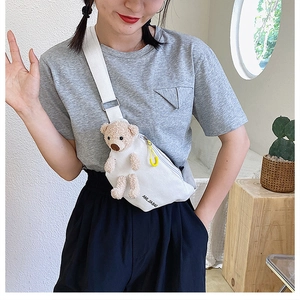 Model wearing white canvas crossbody bag with cute beige plush bear charm detail