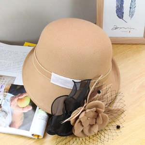 Détail du chapeau cloche en laine kaki avec fleur et voilette sur table en bois