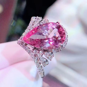 Luxury crown ring with a pear-cut pink stone and diamond halo on a split silver band