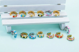 Ear cuff colorati a forma di C in smalto con zirconi su una mini panca di legno