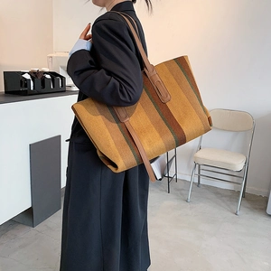 Sac fourre-tout tissé à rayures marron avec lanières en cuir porté par un mannequin