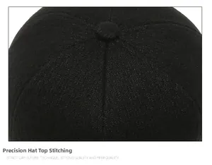 Detailed top view of the six-panel stitching and top button on a black wool baseball cap