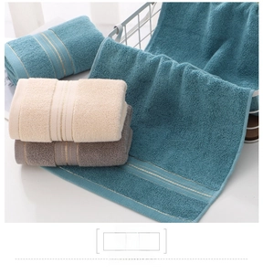 Close-up of thick cotton towels with decorative gold stripe detailing and soft terry texture