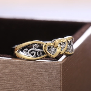 Two-tone heart-shaped ring with cubic zirconia on a brown vintage jewelry box