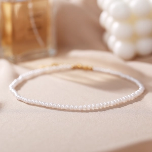 Detail of vintage pearl necklace on pink silk showing golden lobster clasp and chain