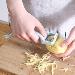 Dual-head vegetable peeler slicing potato julienne strips on a wooden board