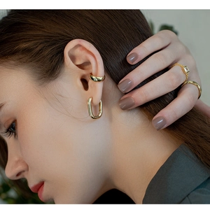 Close-up of polished gold U-shaped earrings and rings set on a model showing sleek details