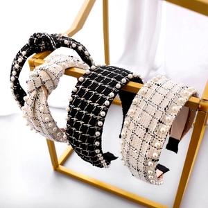 Detail showing vintage plaid tweed headbands with hand-sewn pearls on a gold display stand