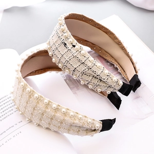 Close-up of tweed knotted headband with double rows of pearls on white magazine