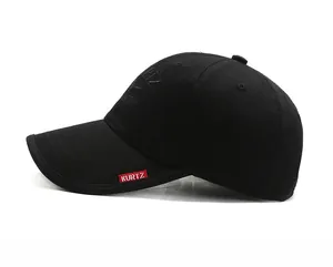 Detail of a black cotton baseball cap showing red Kurtz woven label on the brim side