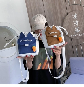 Détail de sacs seaux en toile avec fermeture à cordon et breloques carottes mignonnes