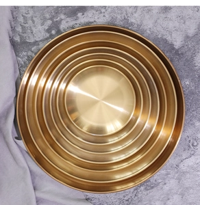 Detail of nested Nordic gold round trays showing the radial brushed metal texture and finish