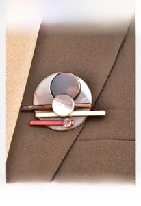 Detailed view of an acrylic brooch with round spliced layers on a brown suit lapel