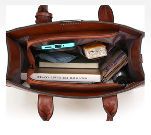 Detail view of the brown leather tote bag interior with dual zipper compartments and pockets