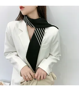 Detailed view of black and white striped silk scarf styled with a white blazer
