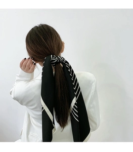 Classic black and white striped silk scarf styled as an elegant hair accessory for a low ponytail