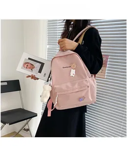 Detail of pink cute backpack featuring cartoon bear patches and white plush pendant