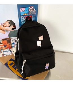 Detail of black nylon backpack with cute bear badges and white Duociyuan logo branding