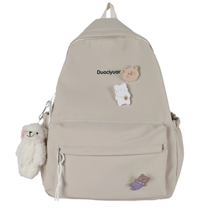 Mochila minimalista de lona beige con insignia de oso y colgante de peluche sobre fondo blanco