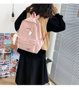 Detailed view of pink school backpack with cute pins and plush charm worn by model