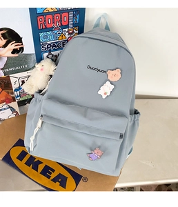 Close-up of light blue nylon backpack featuring cute bear badges and embroidery detail