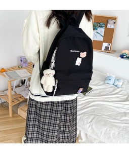 Detail of black canvas backpack with cartoon bear charms and Duociyuan text print