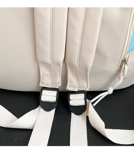 Detailed close-up of cream canvas backpack strap with black adjustable plastic buckle