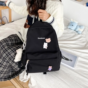 Detailed view of black nylon backpack with cute bear patches and Duociyuan logo branding