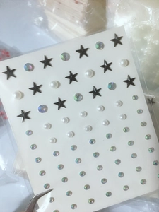 Detailed view of DIY eye makeup stickers with black stars, white pearls and rhinestones