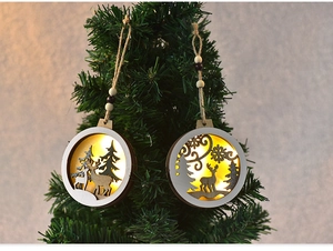 Detail of wooden Christmas ornament with warm LED light featuring reindeer and pine trees
