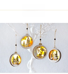 Close-up of four lighted wooden Christmas ornaments featuring reindeer and forest scenes