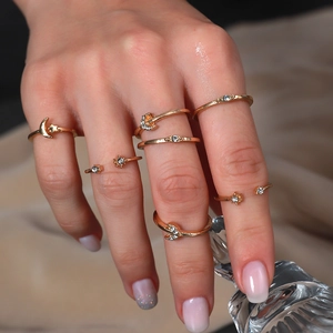 Close-up of gold moon and star stacking rings with crystal accents on a model's hand