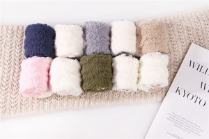 Close-up of rolled coral fleece sleep socks in various colors on a soft knit background