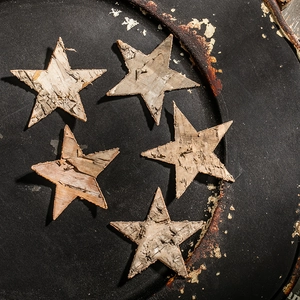 Five rustic birch bark star ornaments on a dark tray for Christmas garden decoration