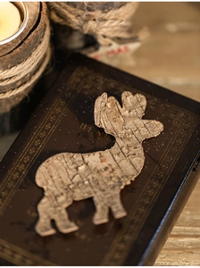 Macro detail of a natural bark reindeer ornament on a rustic vintage wooden surface