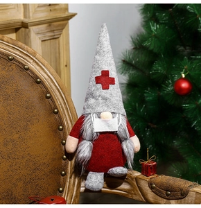 Détail d'un gnome de Noël infirmière avec croix rouge posé sur un fauteuil
