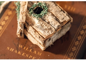 Nahaufnahme eines Rinden-Weihnachtshauses mit Kranz auf einem Vintage-Buch