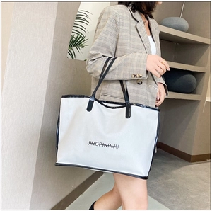Modern white tote bag with black trim and letters, shown with a stylish casual outfit