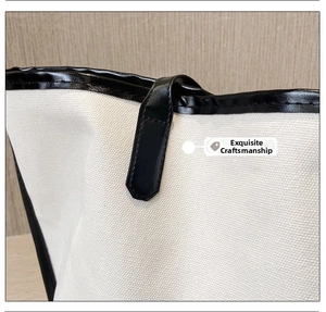 Detail of reinforced stitching on canvas tote with black leather handle and edging