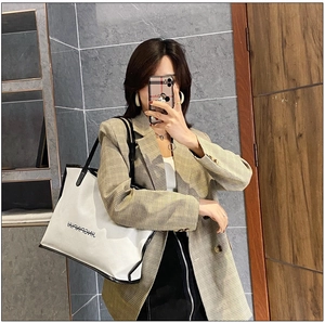 Mirror selfie showing the large cream tote bag with black leather trim on model in a suit
