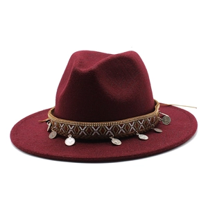 Close-up of wine red fedora hat with bohemian woven band and vintage silver metal coins