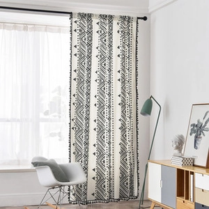 Detail of bohemian geometric curtain with black tassel trim and cream linen texture
