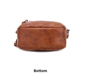 Detail view of the brown quilted leather crossbody bag showing the curved bottom base