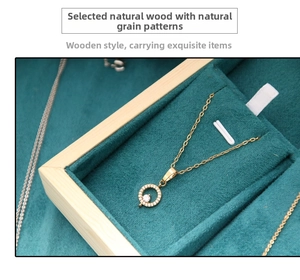Detail of a gold necklace with a circular diamond pendant in a green velvet jewelry tray