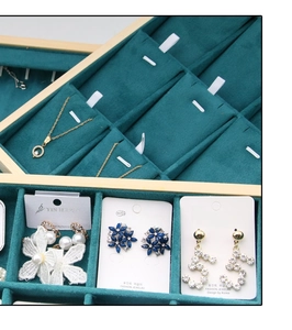 Detailed view of dark green velvet jewelry tray featuring luxury gold and crystal earrings